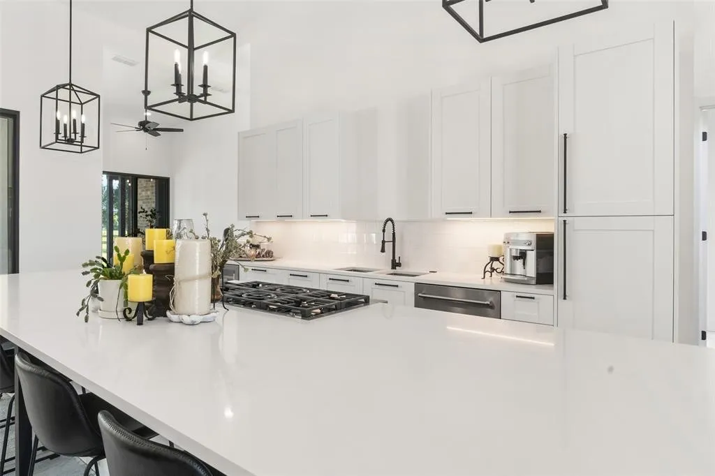 Kitchen with a kitchen bar, sink, white cabinetry, pendant lighting, and stainless steel appliances