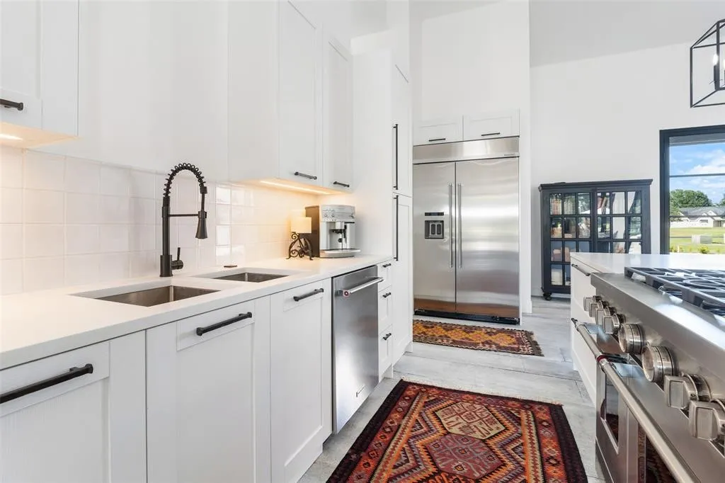 Kitchen featuring white cabinetry, high quality appliances, sink, and tasteful backsplash