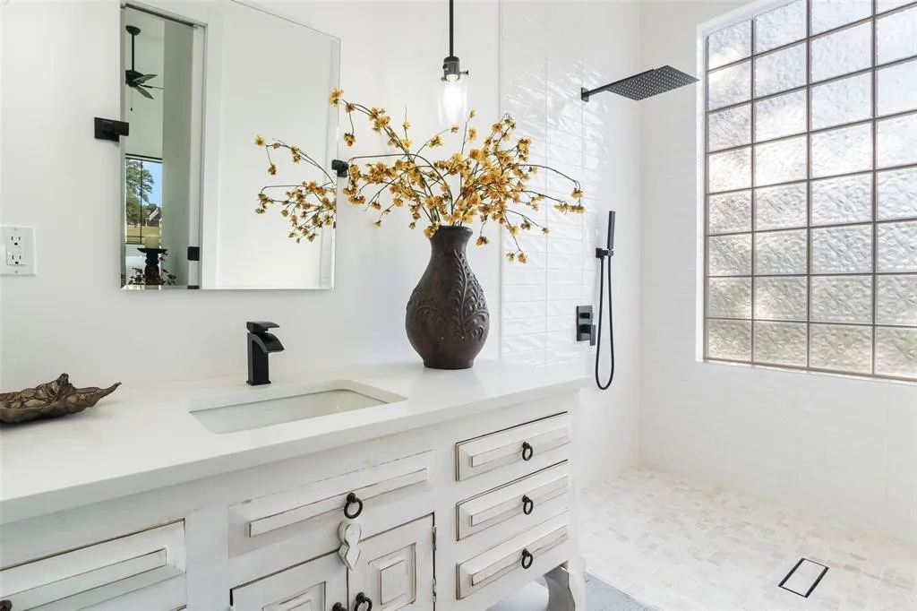Bathroom with tiled shower, vanity, and a wealth of natural light