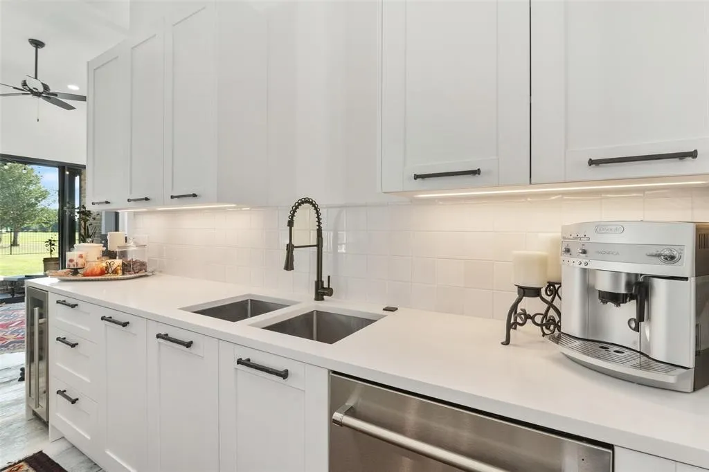 Kitchen with white cabinetry, sink, decorative backsplash, and dishwasher