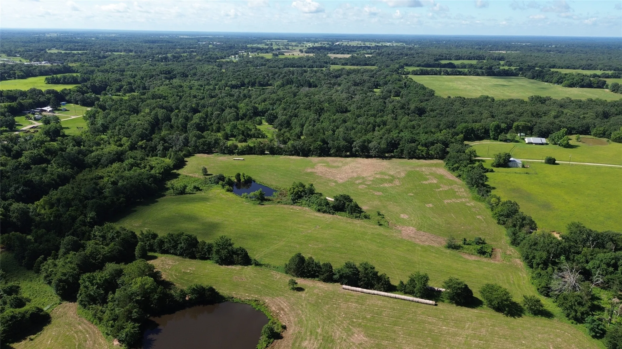 Overview of rural landscape featuring a heavily wooded area and a large body of water