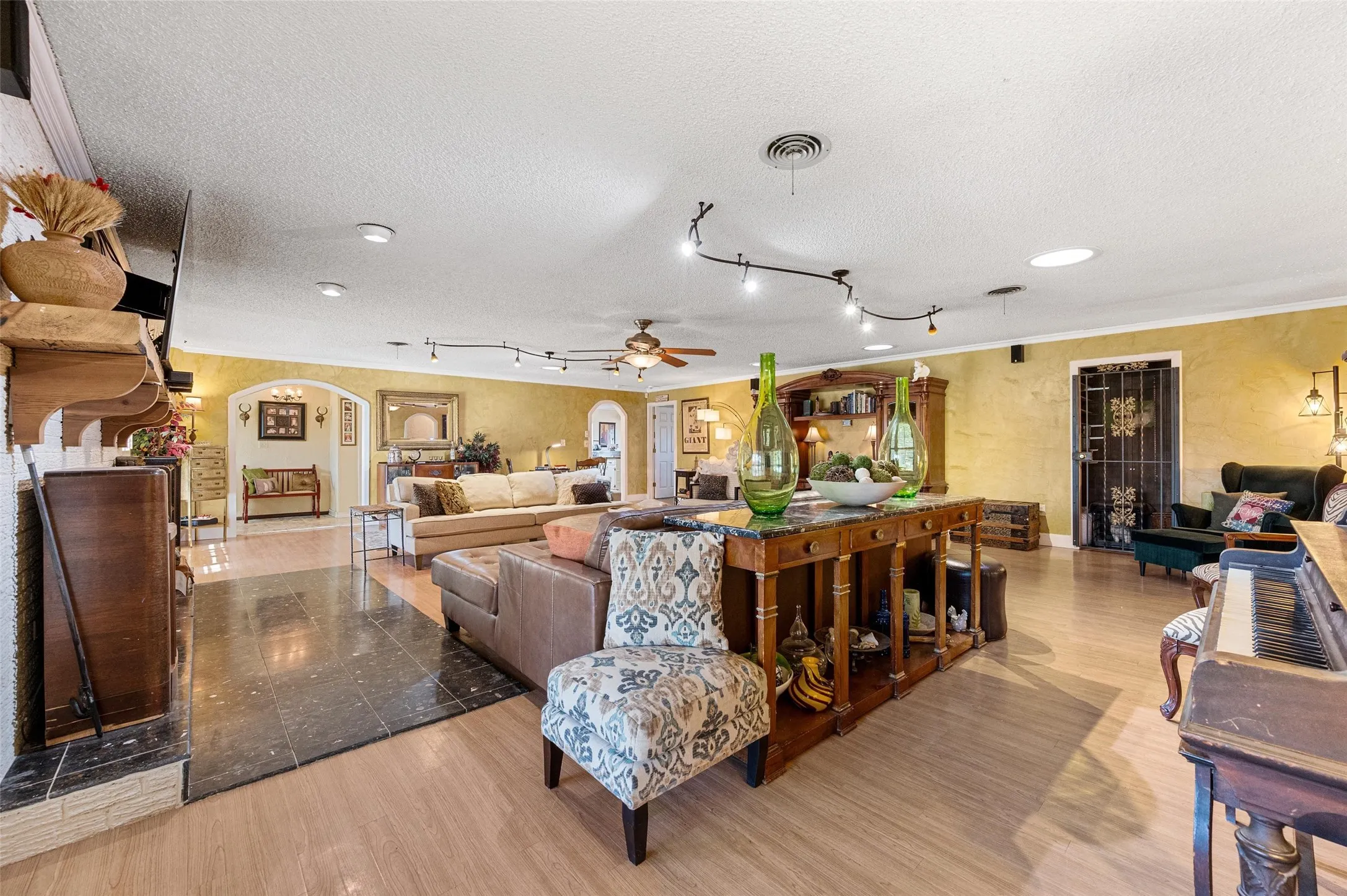 Living room featuring light wood-type flooring, arched walkways, visible vents, and a textured ceiling