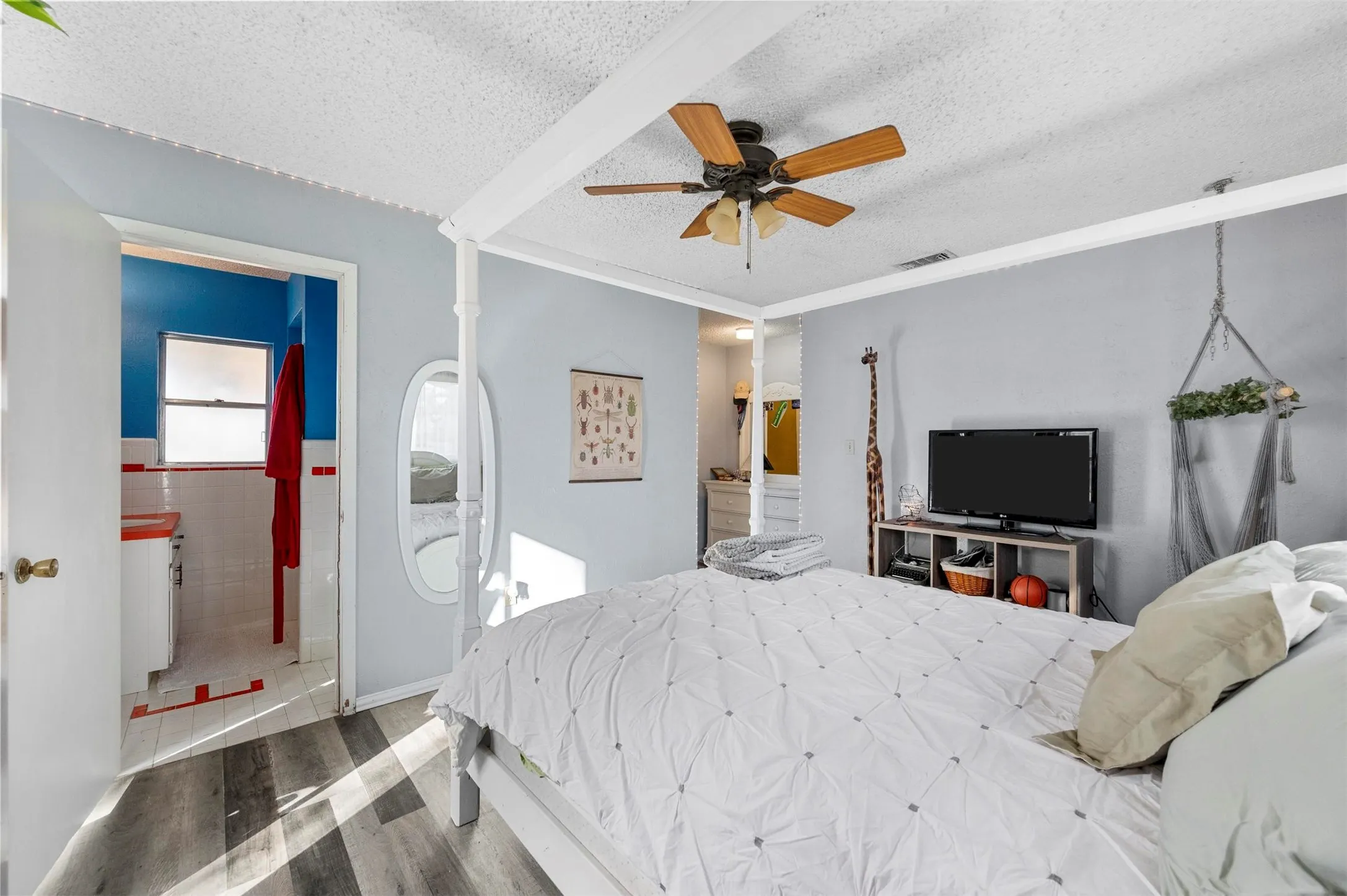 Bedroom featuring a textured ceiling, wood finished floors, a ceiling fan, tile walls, and crown molding