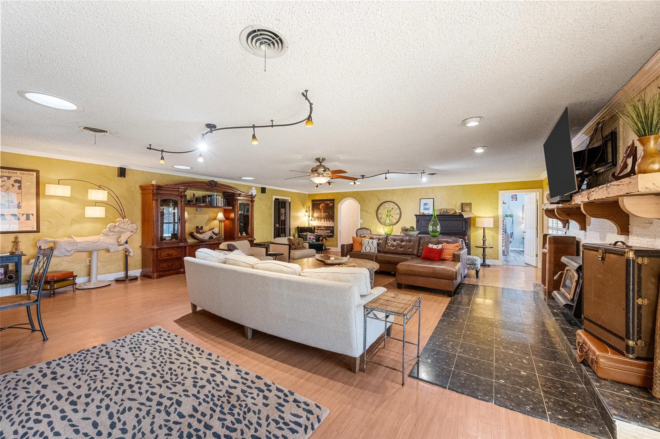 Living area featuring a fireplace, visible vents, ornamental molding, a textured ceiling, and wood finished floors