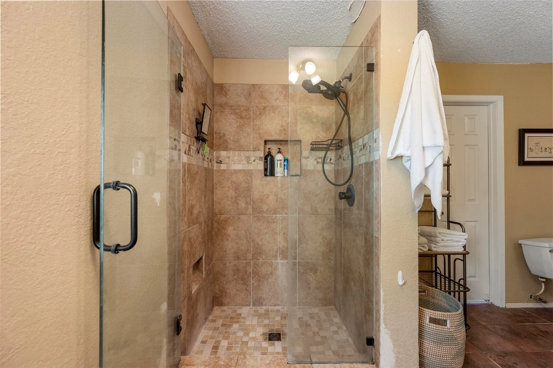 Bathroom featuring toilet, a stall shower, and a textured ceiling