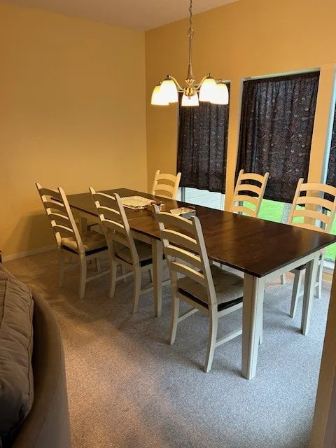 Dining room featuring a chandelier, carpet flooring, and baseboards