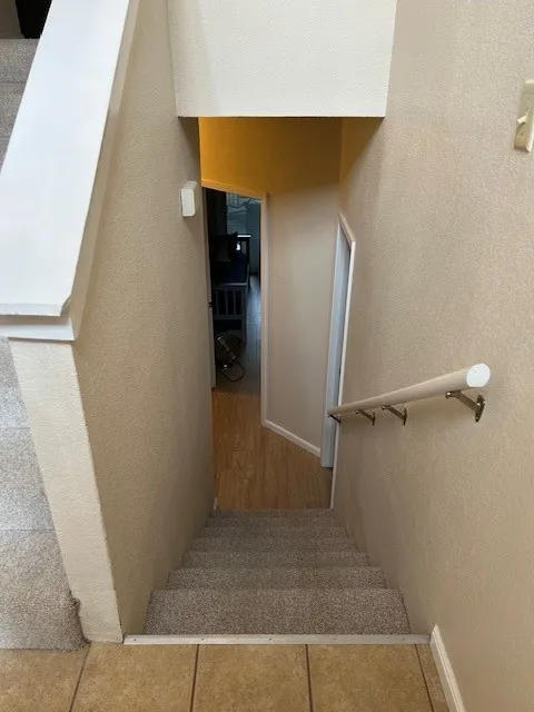 Staircase with a textured wall and baseboards