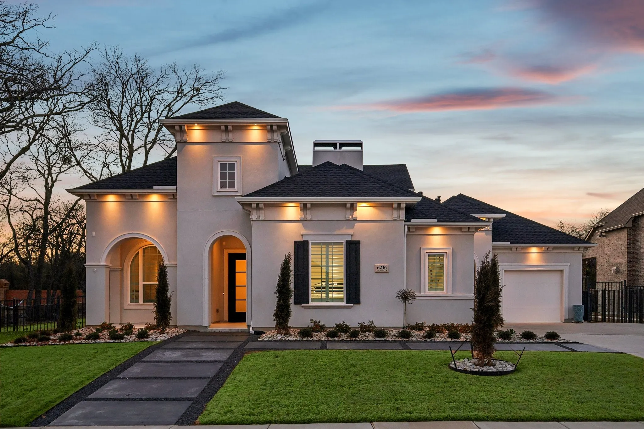 Twilight shot of the front of 6216 Via Italia Drive. Warm down lights enhance the overall beauty of this Mediterranean inspired home.