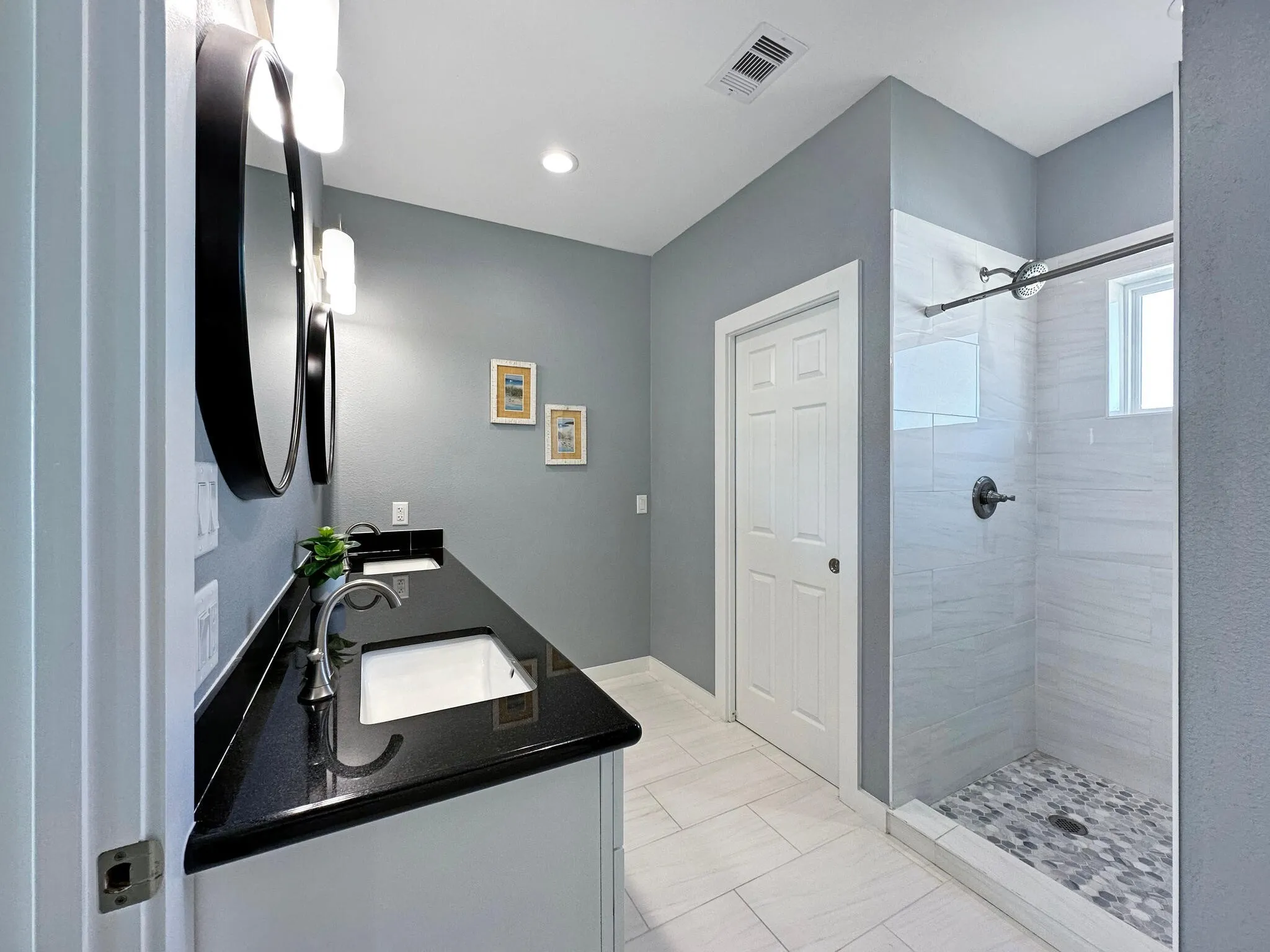 Bathroom with double vanity, a sink, and tiled shower