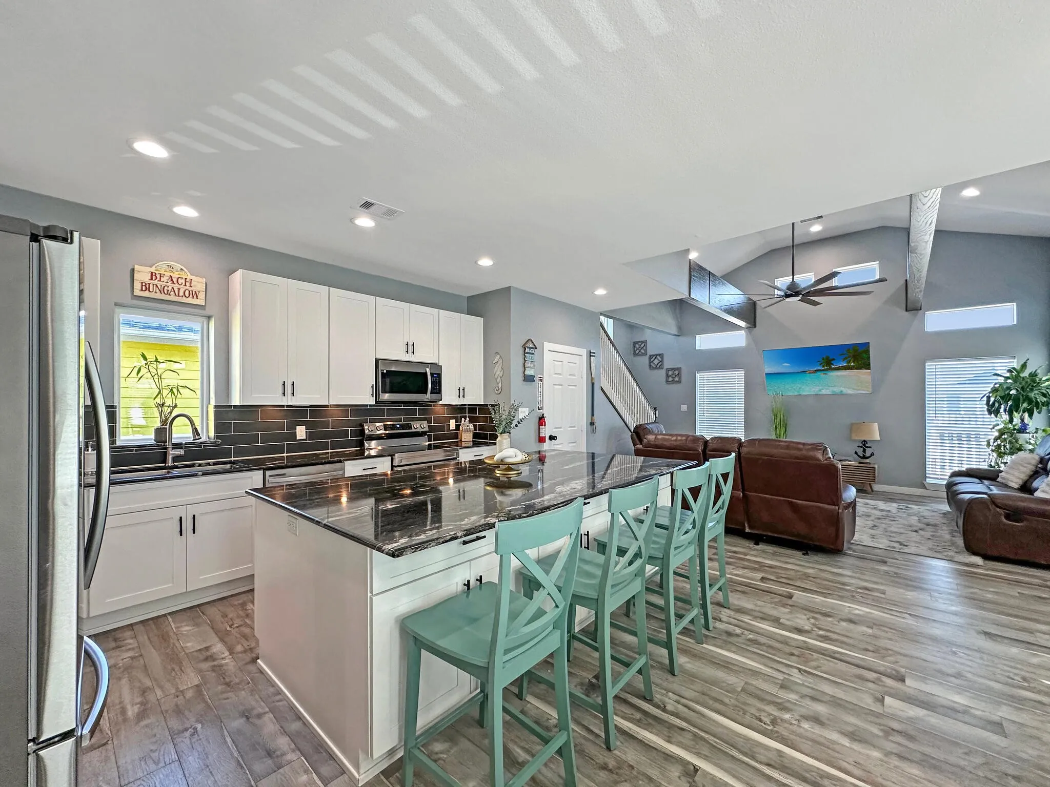 Kitchen with light wood finished floors, open floor plan, vaulted ceiling, stainless steel appliances, and backsplash