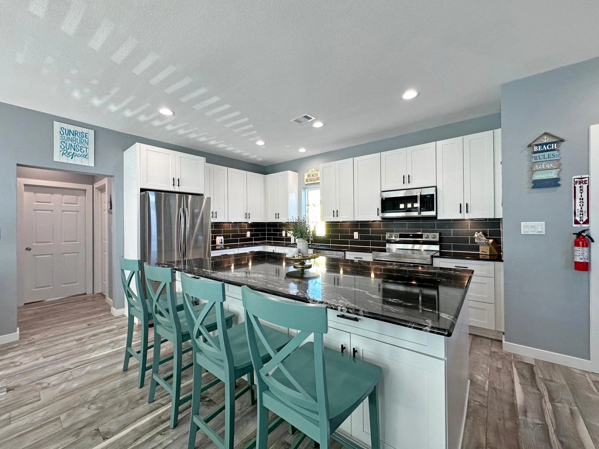 Kitchen featuring a breakfast bar area, tasteful backsplash, light wood-style flooring, appliances with stainless steel finishes, and white cabinetry