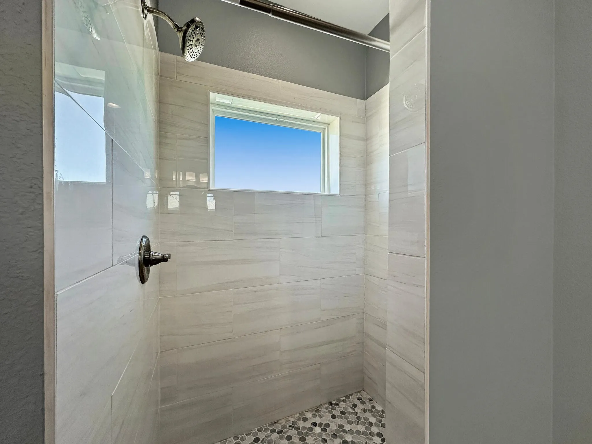 Full bath with a tile shower and a healthy amount of sunlight