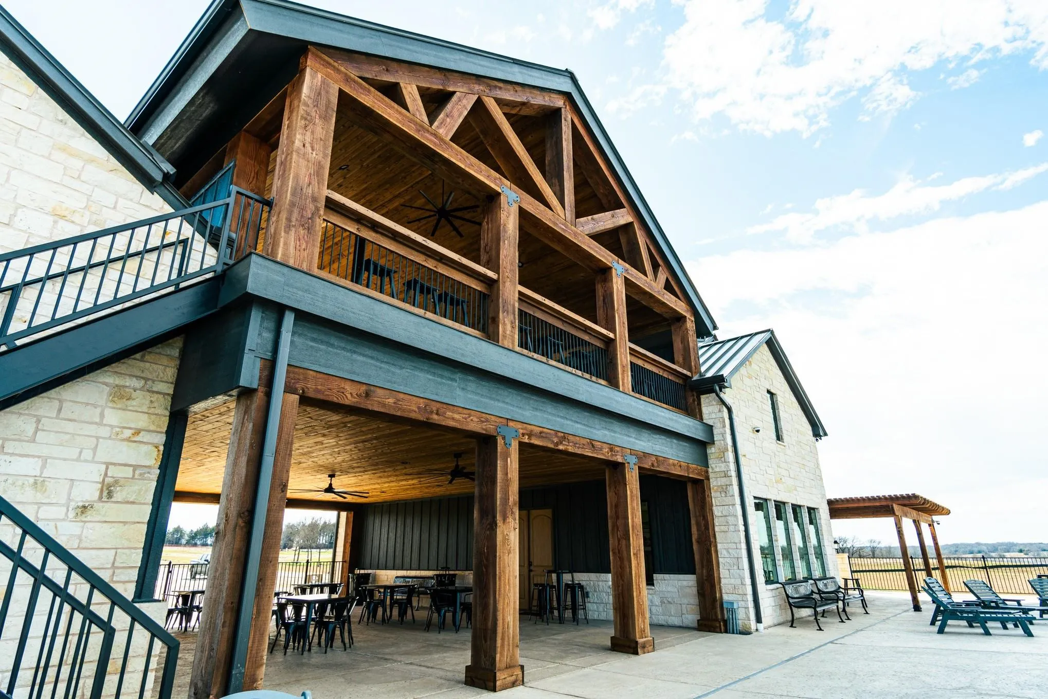 Rear view of house with a balcony, stone siding, outdoor dining space, and a standing seam roof