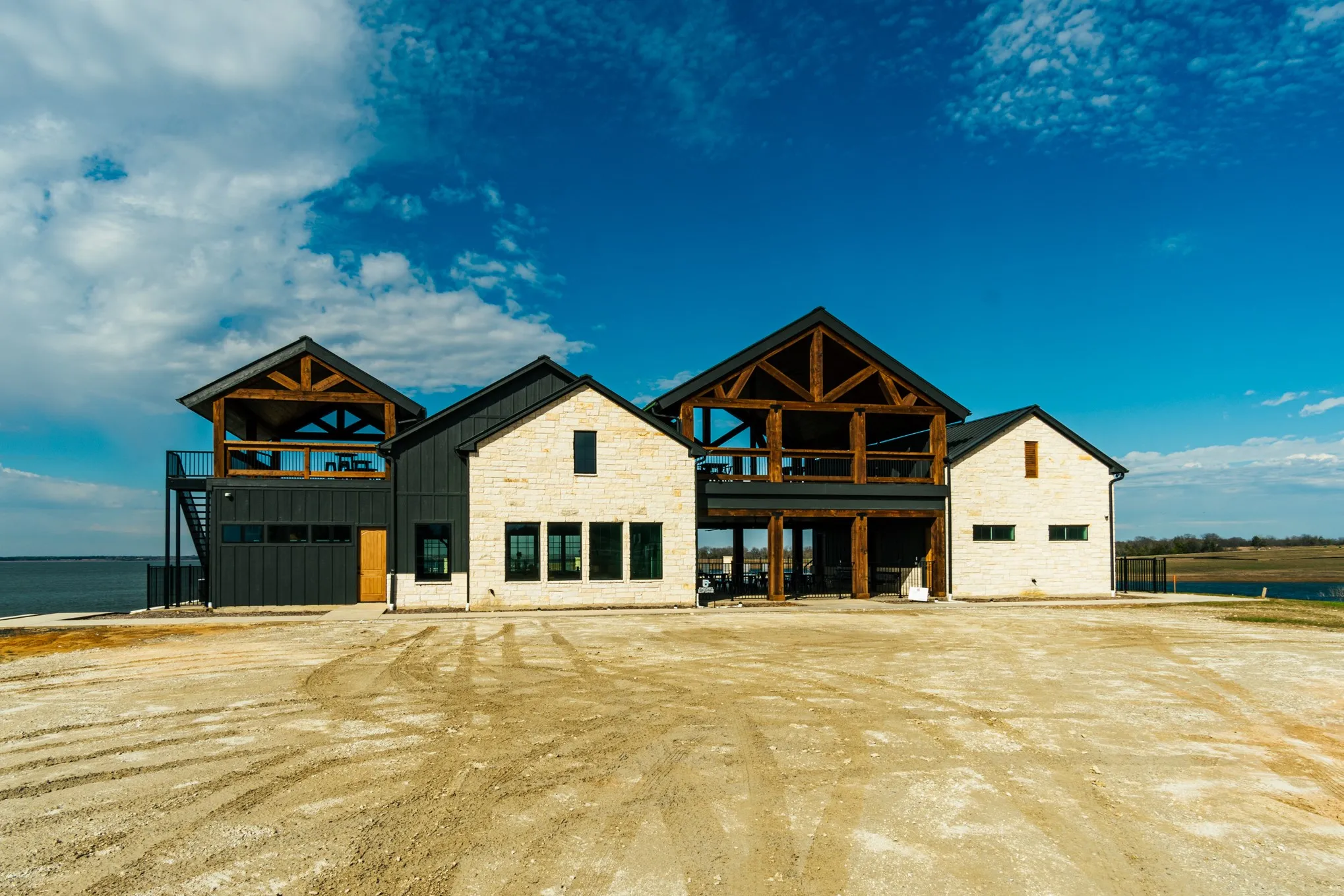 View of front facade featuring a balcony, stone siding, a water view, and board and batten siding