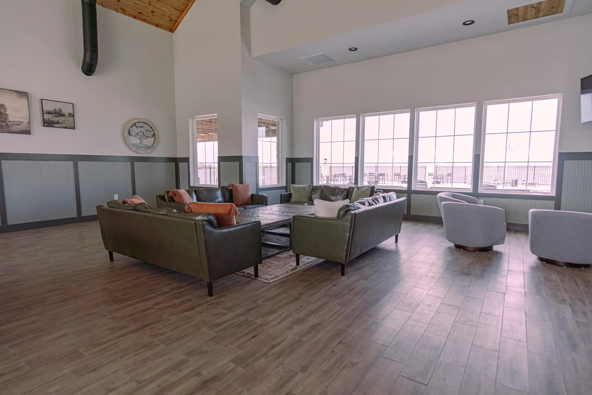Living area with dark wood-style flooring, visible vents, plenty of natural light, and high vaulted ceiling
