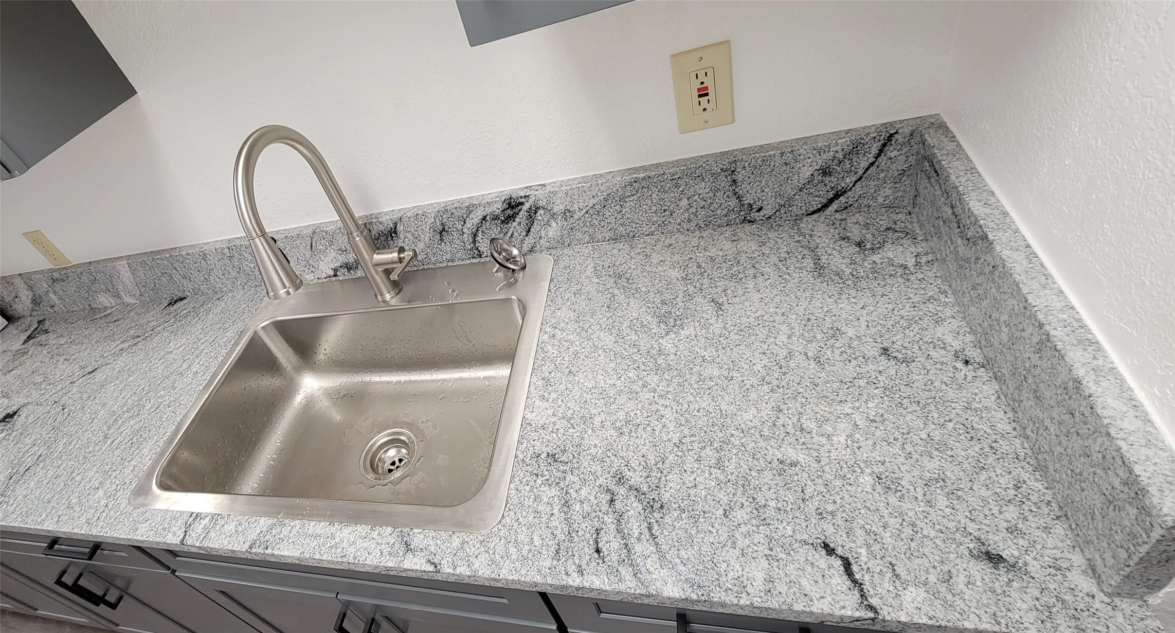 Kitchenette granite counter with backsplash and large sink