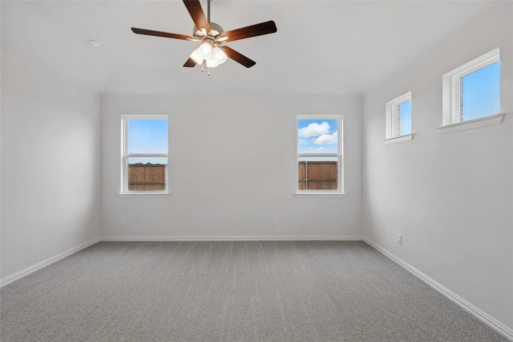 Carpeted spare room with ceiling fan and baseboards