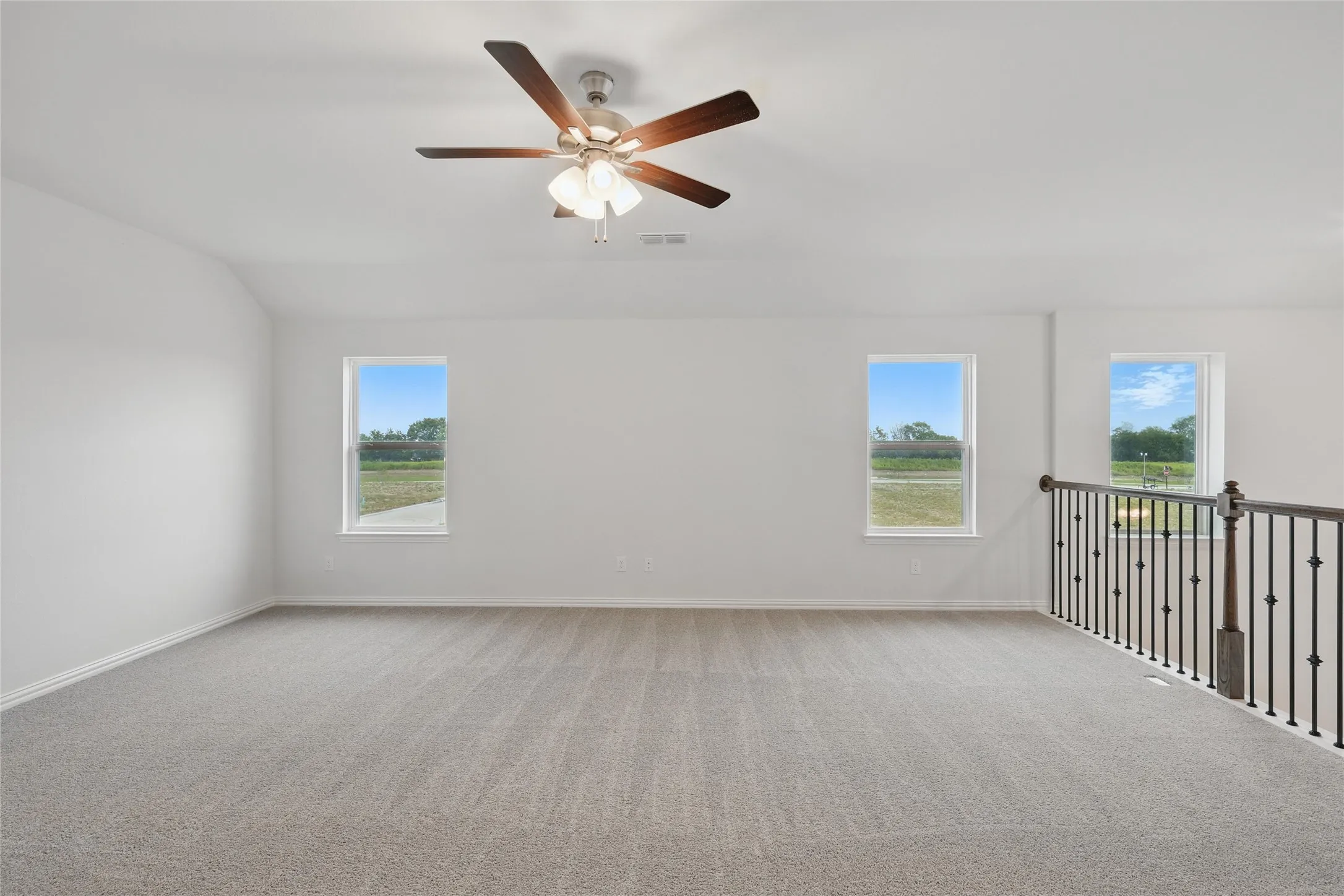Carpeted empty room with a ceiling fan and vaulted ceiling