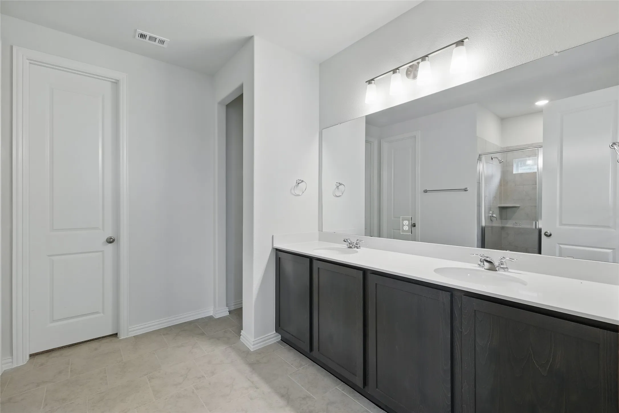 Full bathroom with double vanity and a stall shower