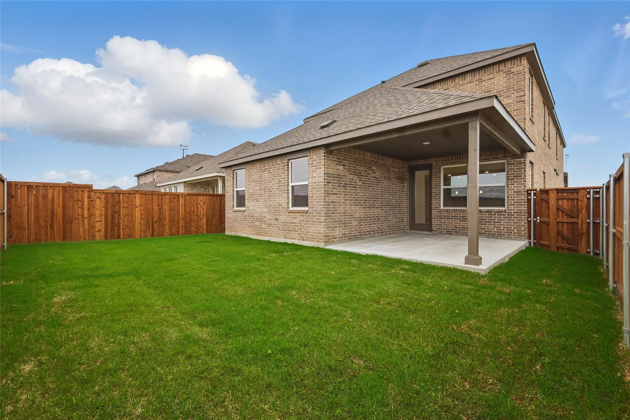 Rear view of property with brick siding, a patio, a fenced backyard, and a shingled roof