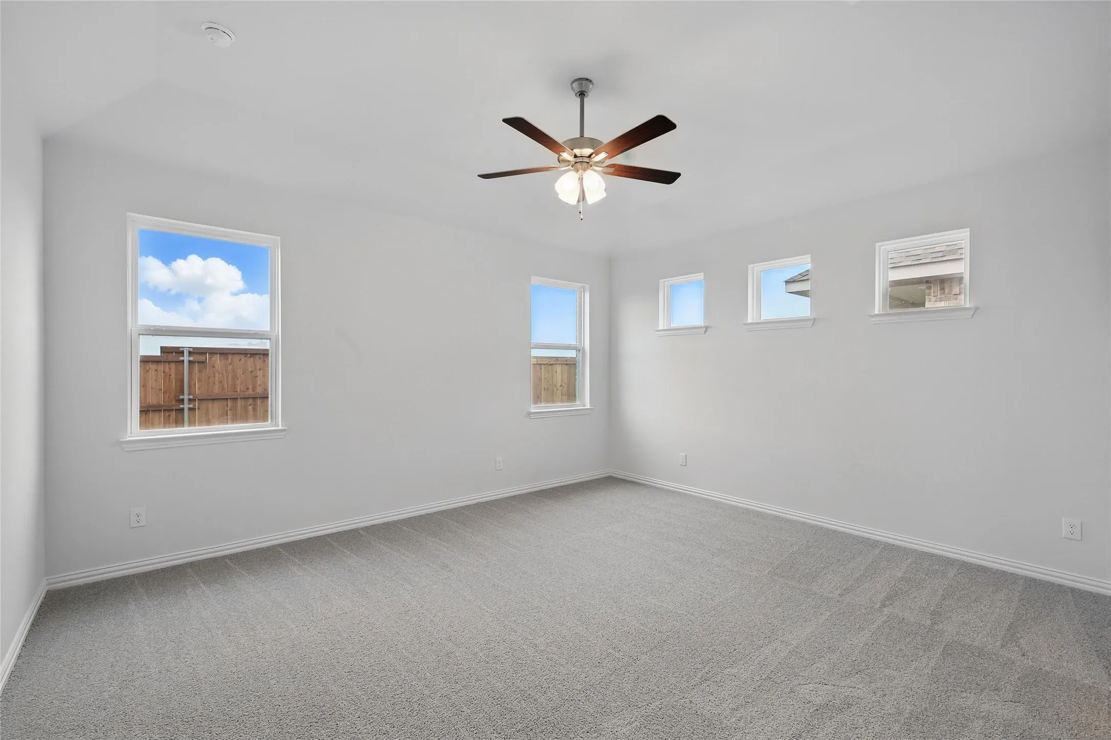 Carpeted spare room featuring baseboards and a ceiling fan