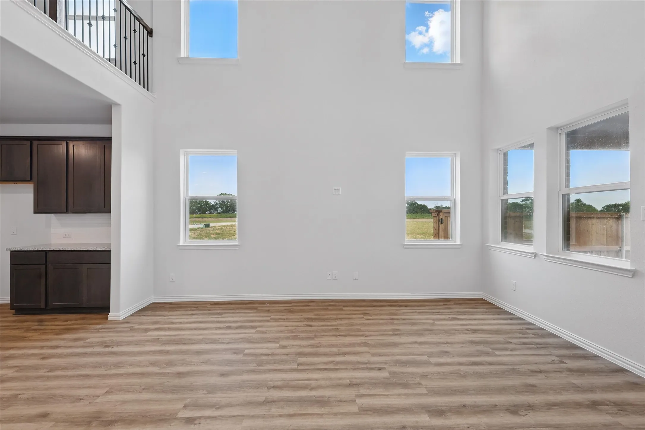 Unfurnished living room featuring a towering ceiling and light wood-style flooring