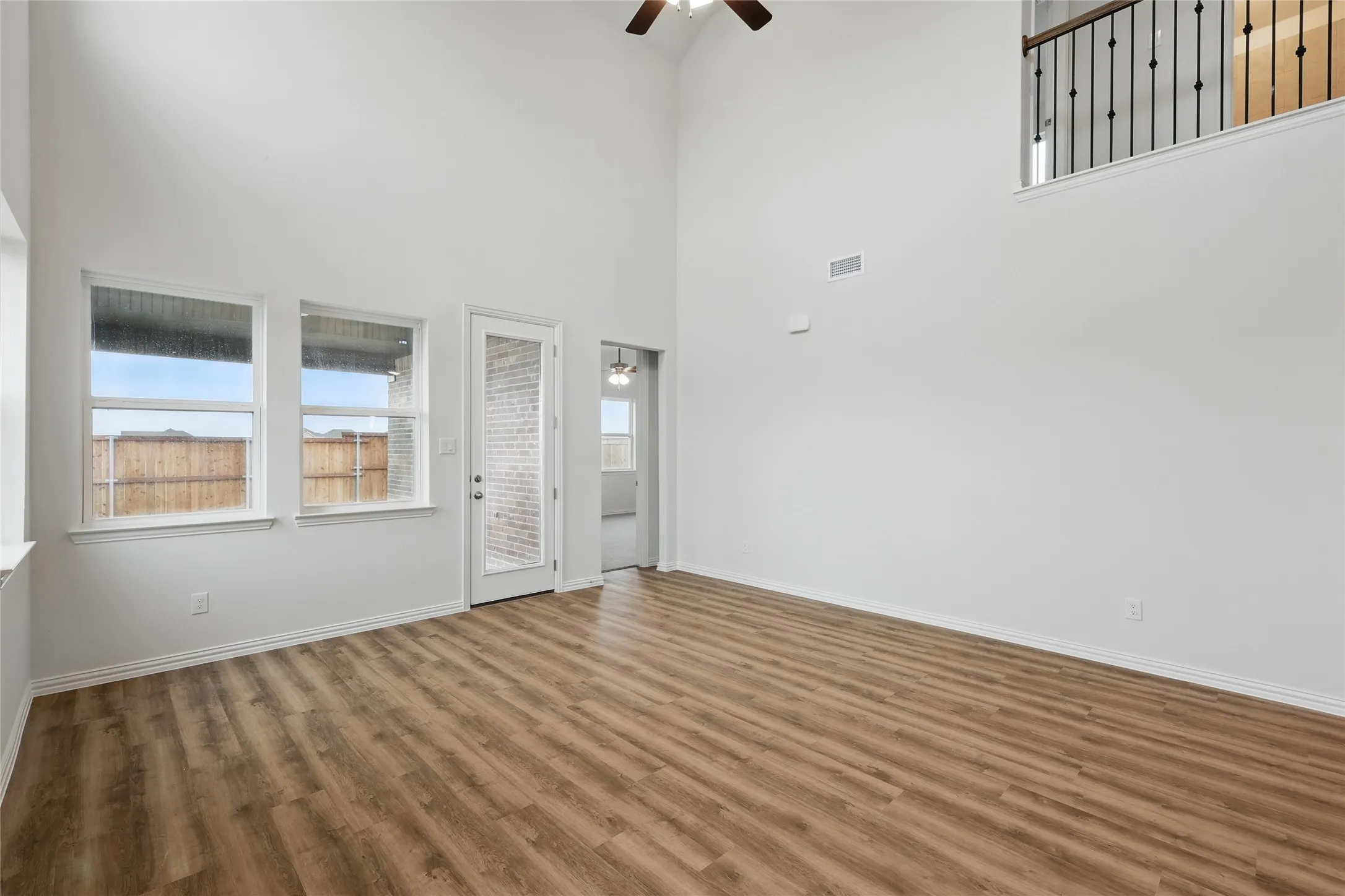 Spare room with wood finished floors, a ceiling fan, and a high ceiling
