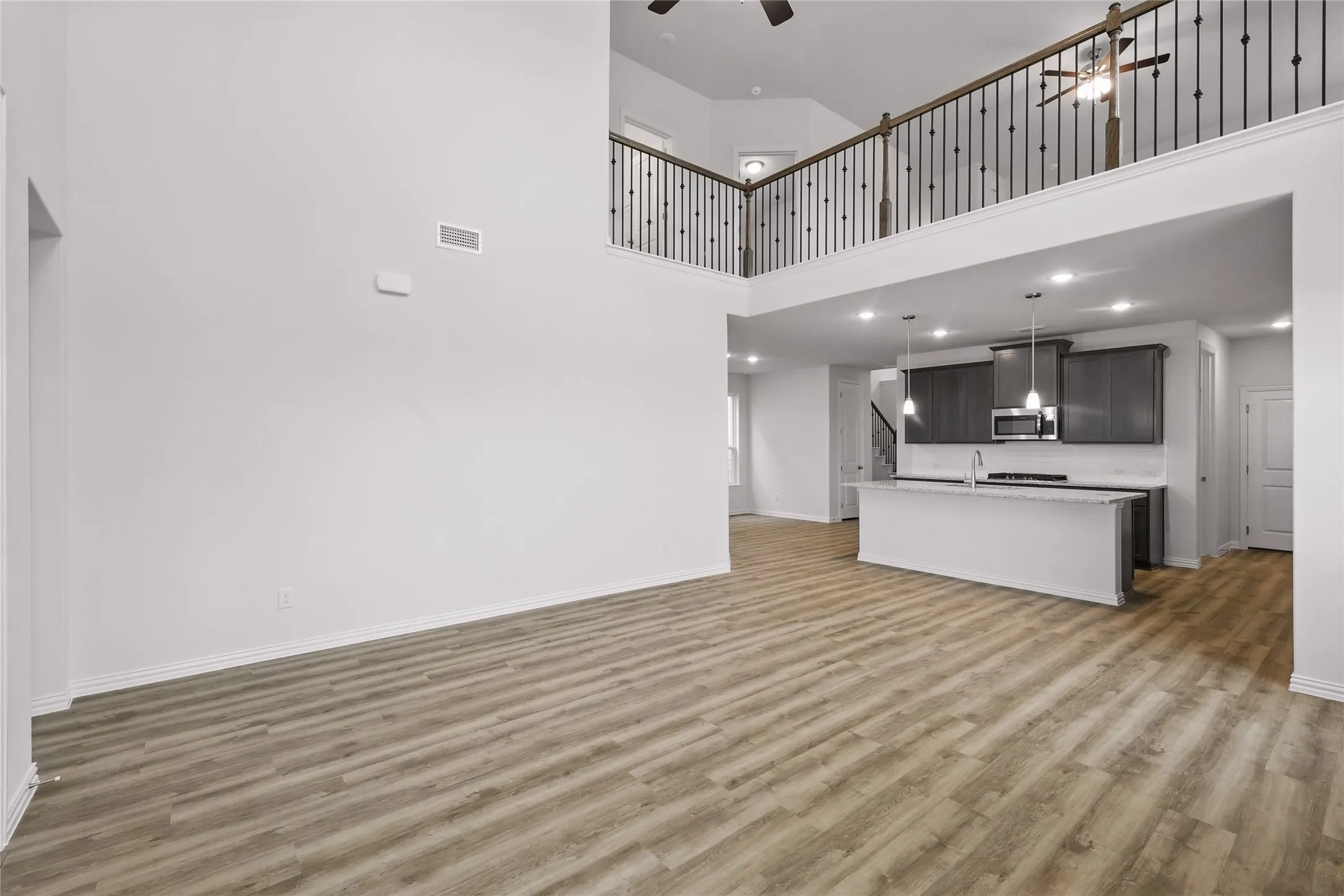 Unfurnished living room with a ceiling fan, a towering ceiling, light wood-style flooring, and recessed lighting