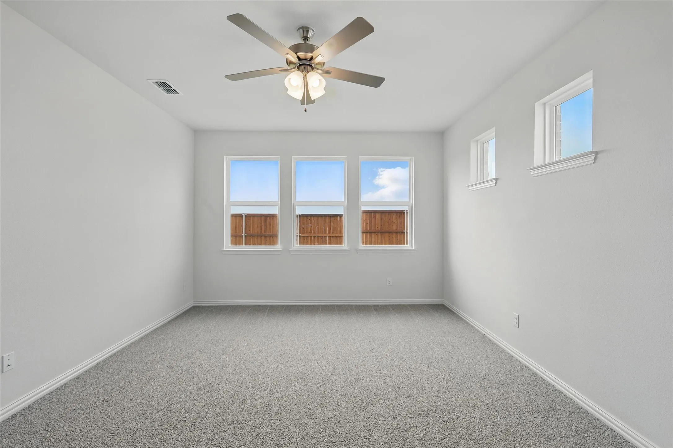 Carpeted spare room featuring ceiling fan and baseboards