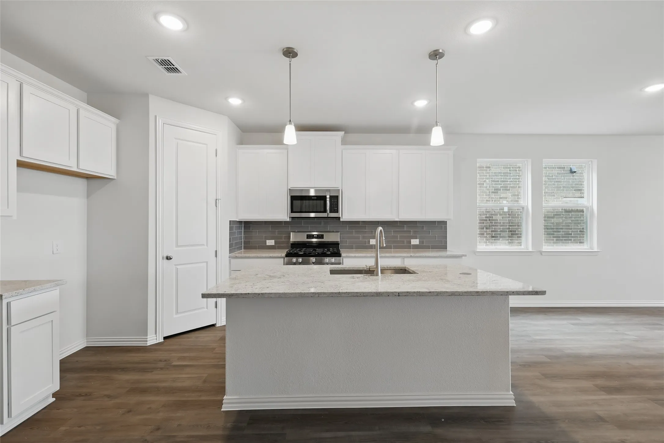Kitchen with tasteful backsplash, white cabinetry, dark wood-style floors, and recessed lighting
