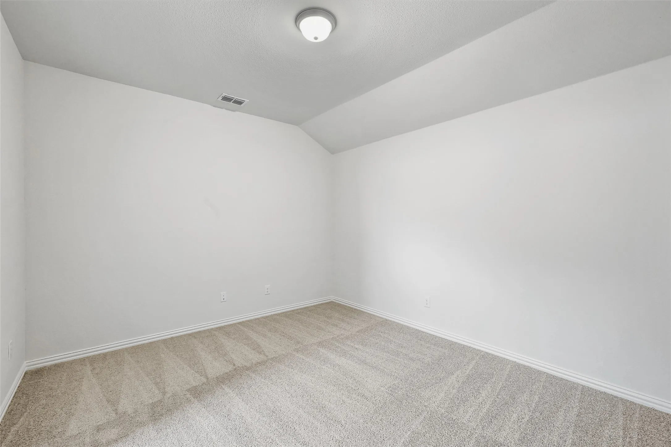 Carpeted empty room with vaulted ceiling and baseboards