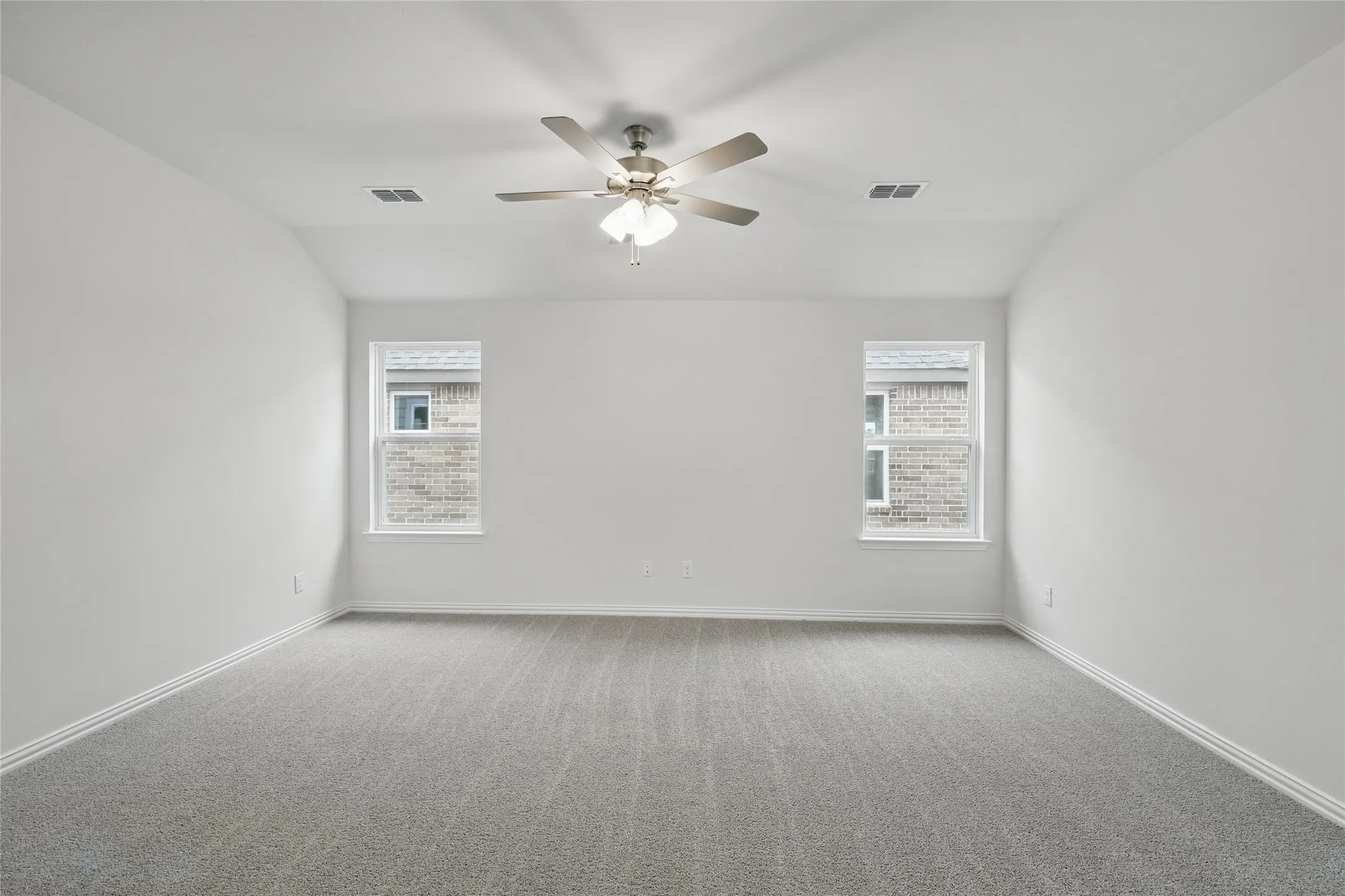 Carpeted empty room with vaulted ceiling and a ceiling fan