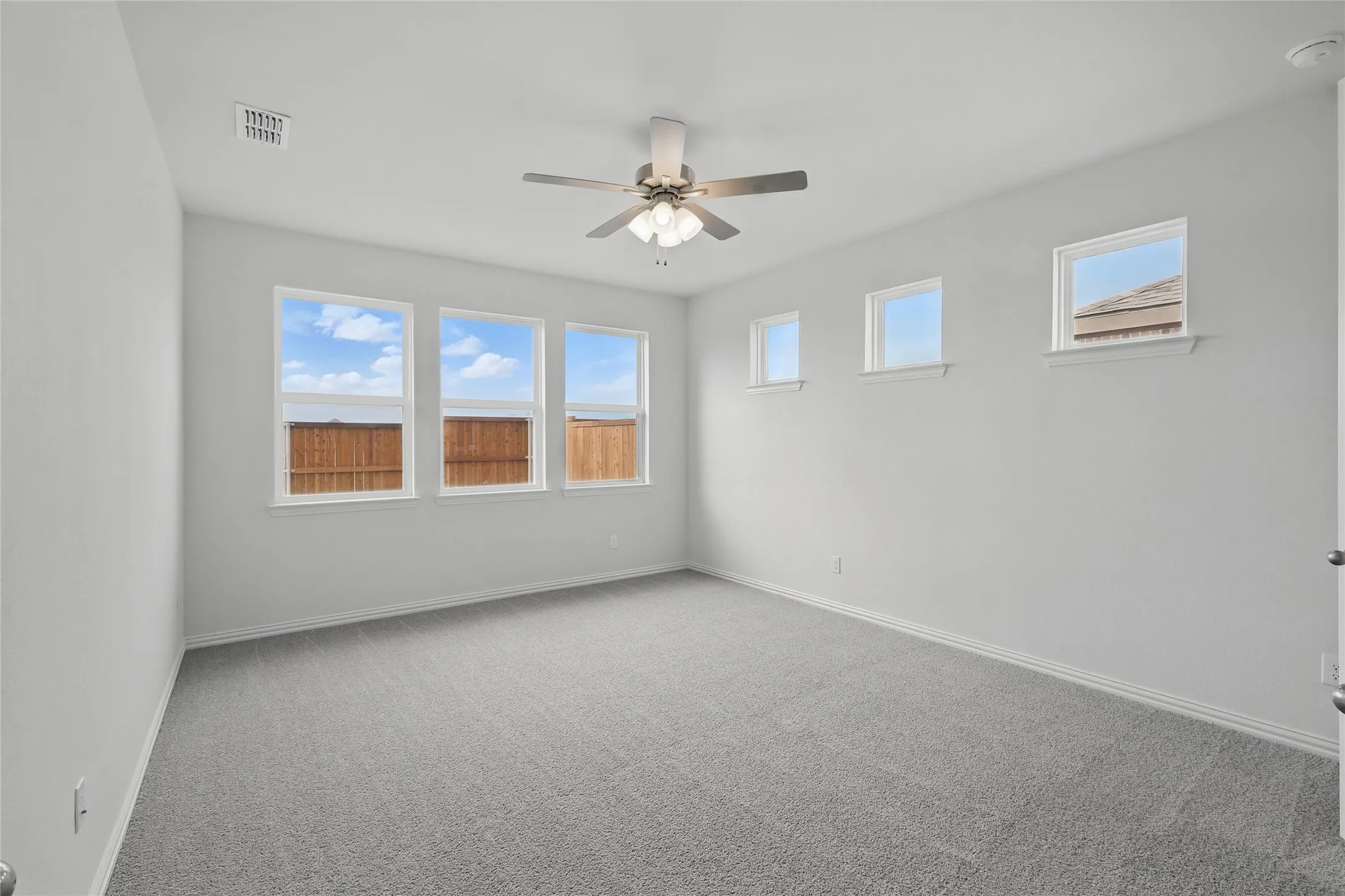 Carpeted spare room featuring baseboards and a ceiling fan