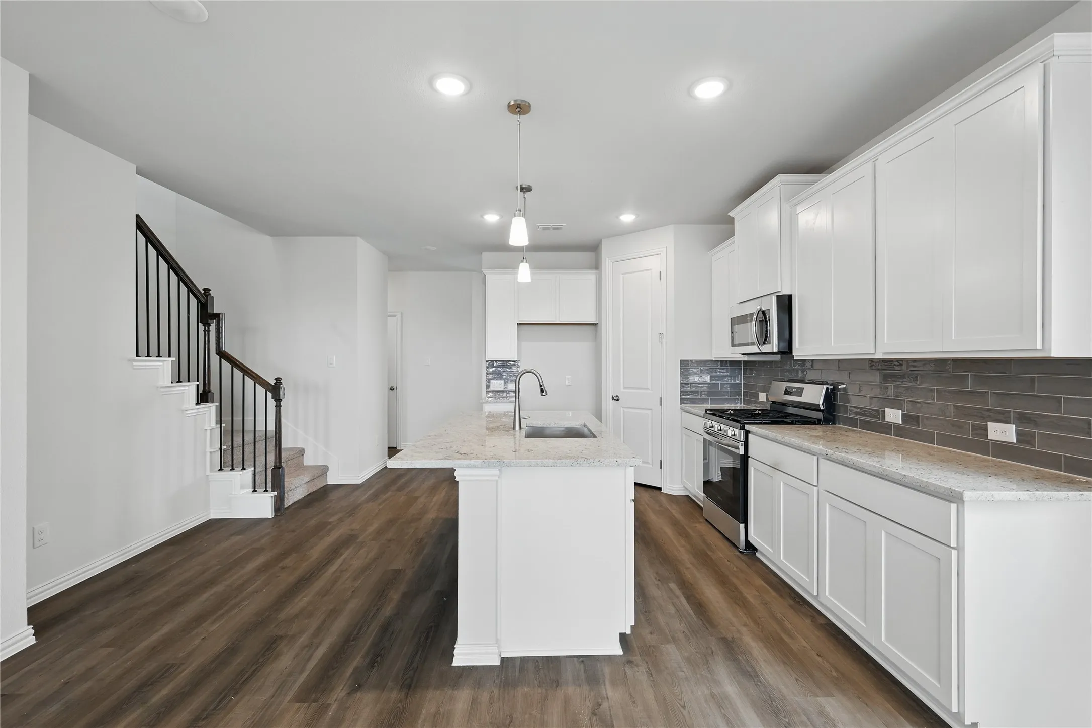 Kitchen featuring stainless steel appliances, tasteful backsplash, an island with sink, dark wood-type flooring, and recessed lighting