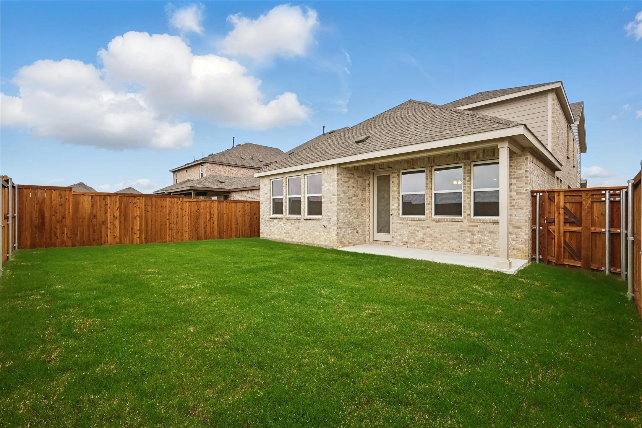 Rear view of property with brick siding, a gate, and a fenced backyard