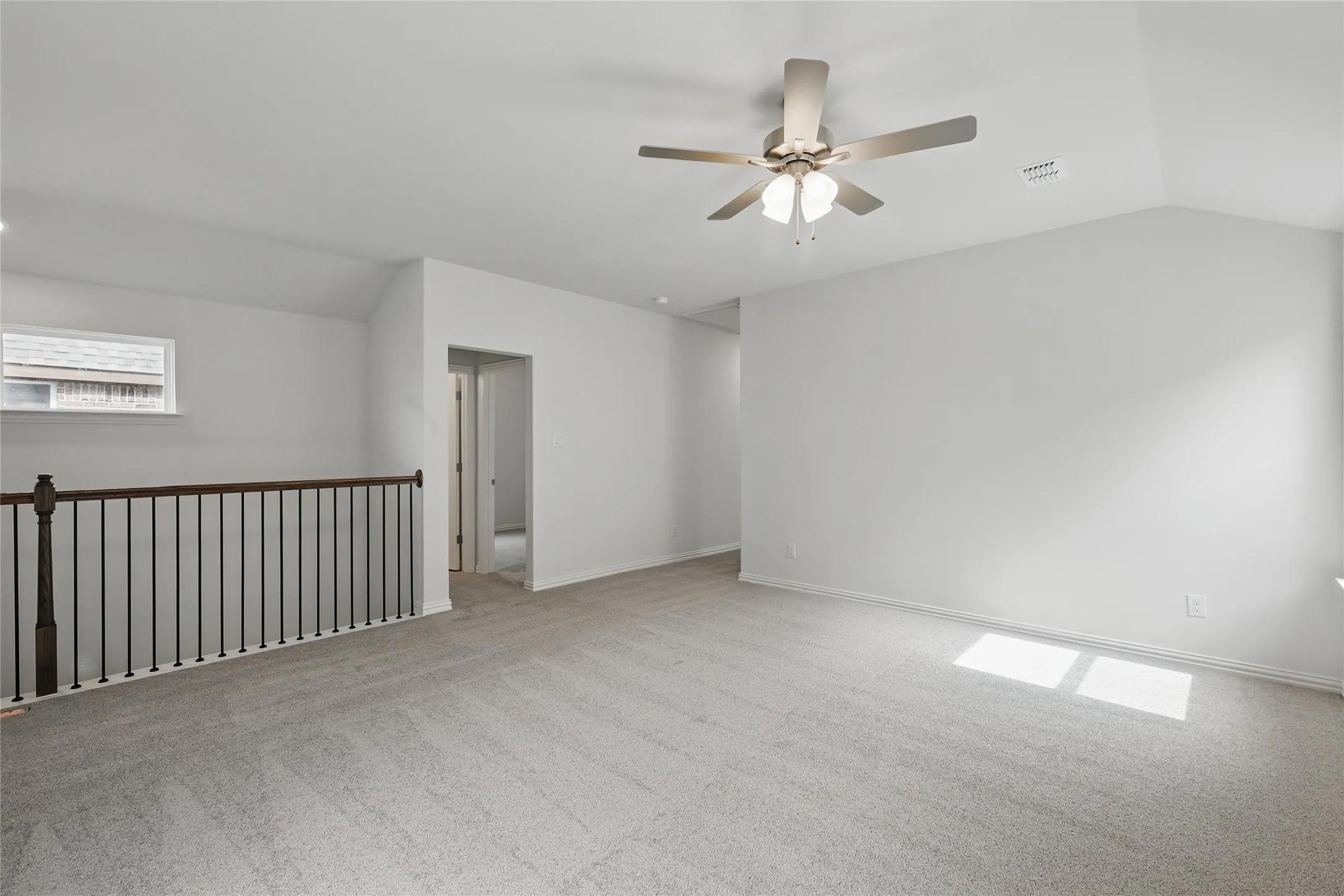 Spare room featuring light colored carpet, a ceiling fan, and vaulted ceiling