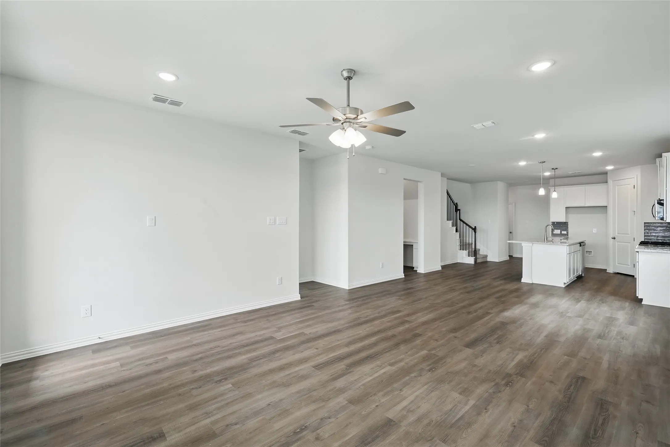 Unfurnished living room featuring recessed lighting, stairway, dark wood-style floors, and ceiling fan