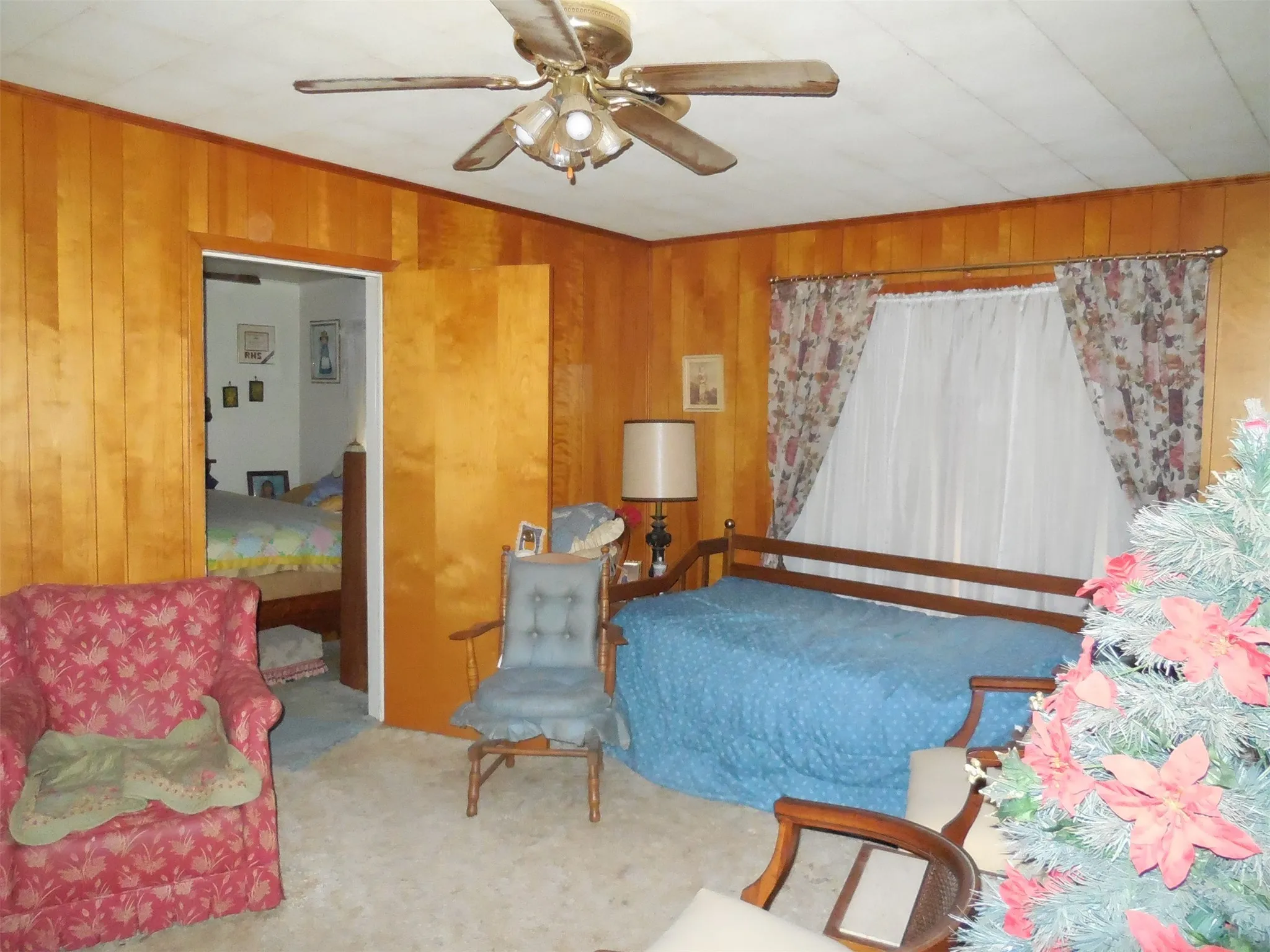 Sitting room featuring ceiling fan, wood walls, carpet flooring, and crown molding