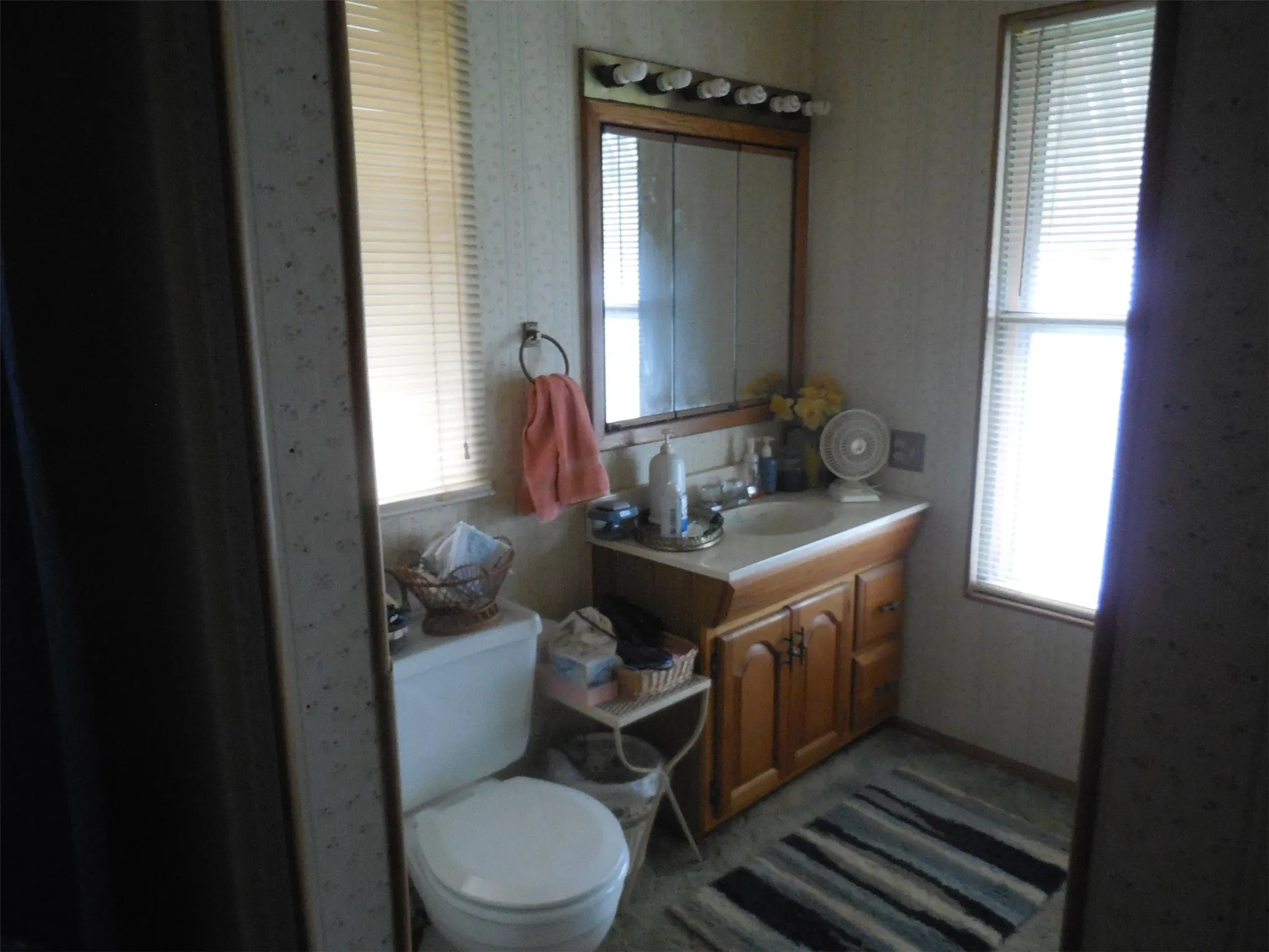 Bathroom featuring a healthy amount of sunlight, wallpapered walls, and vanity