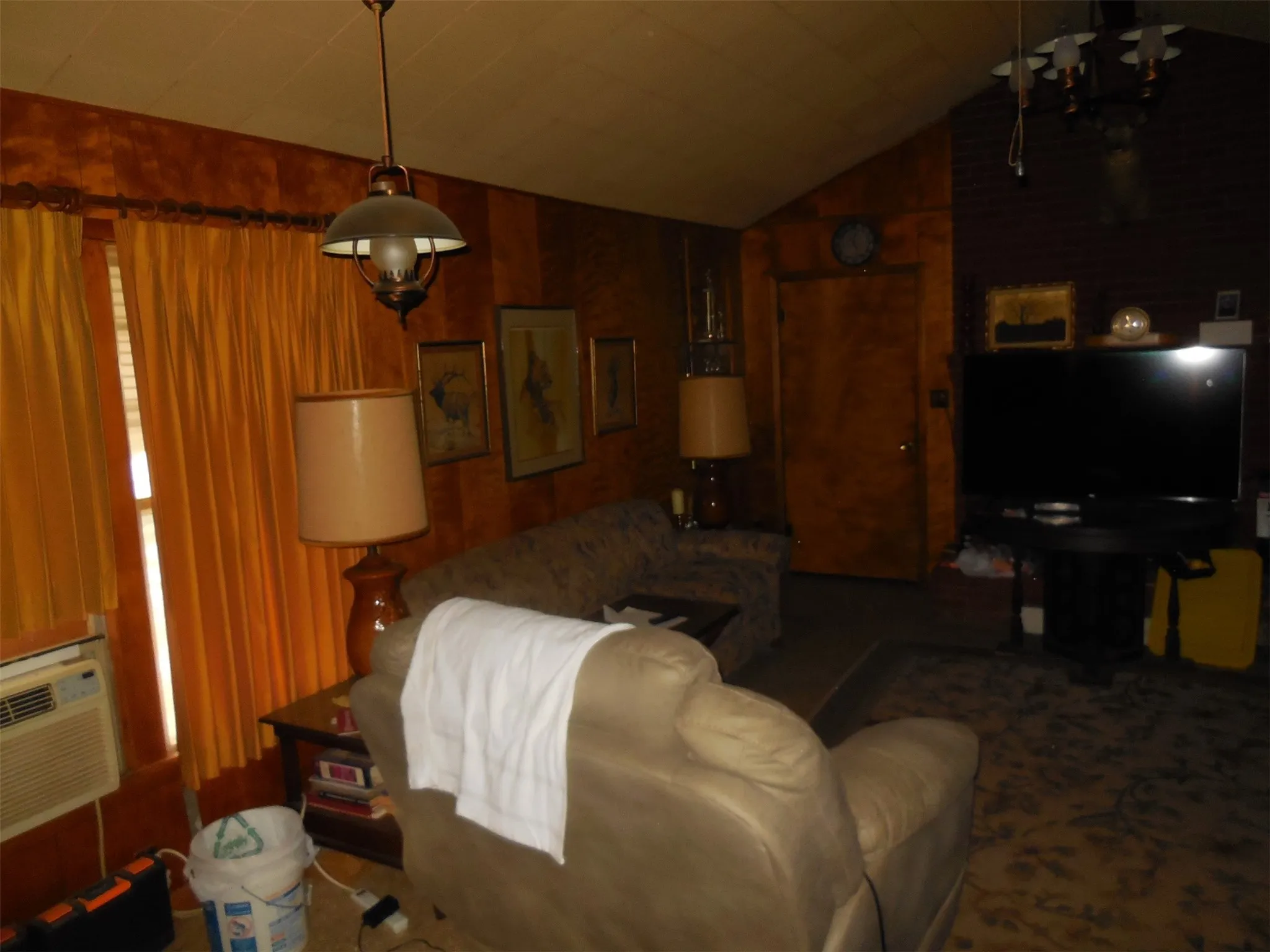 Den with lofted ceiling, cooling unit, and wooden walls
