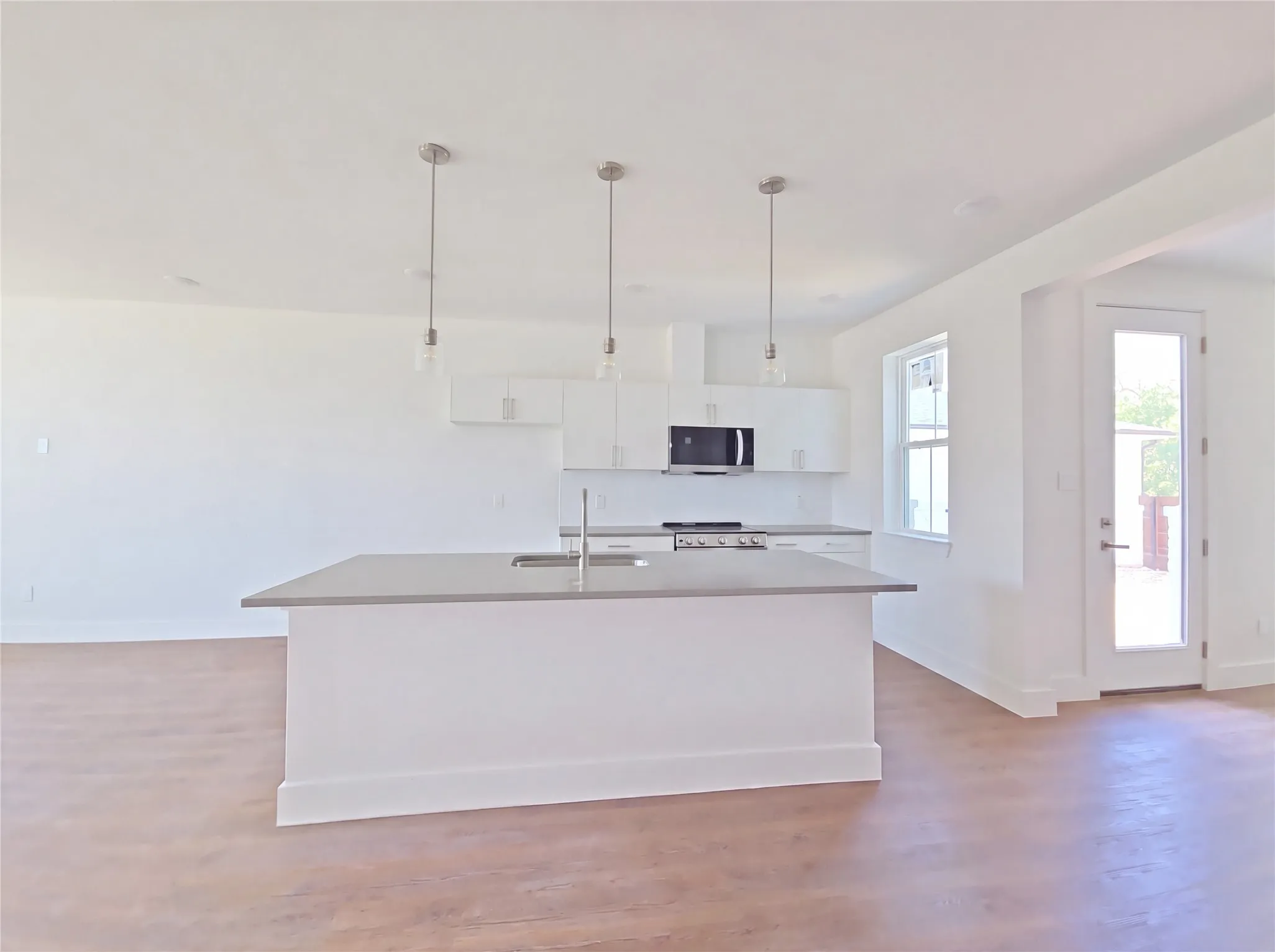 Open-concept kitchen with a central island, stainless steel appliances, and white cabinetry