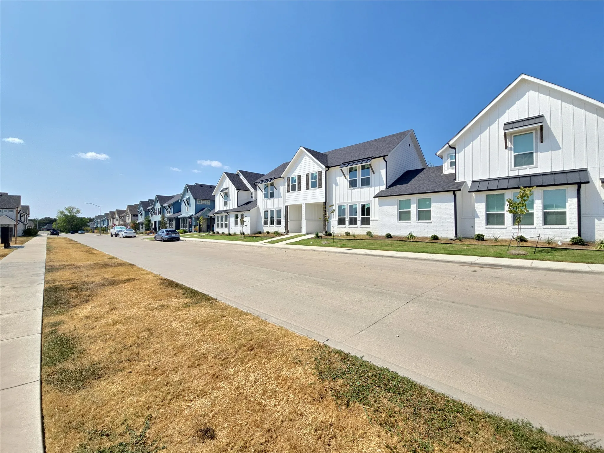 Modern farmhouse architectural style featuring vertical white siding and black-framed windows with dark awnings