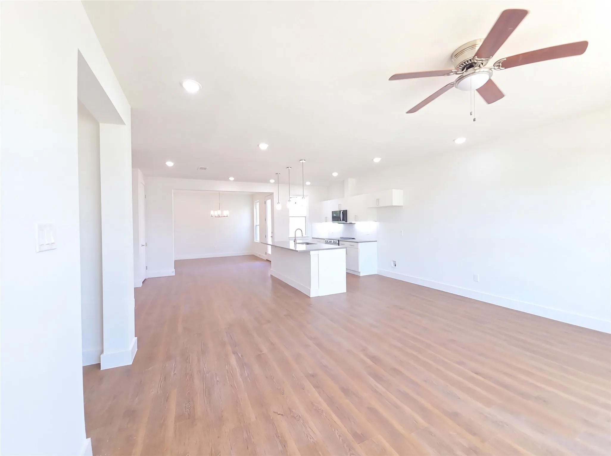 Open-concept living space featuring wood-finish flooring, recessed lighting, and a ceiling fan