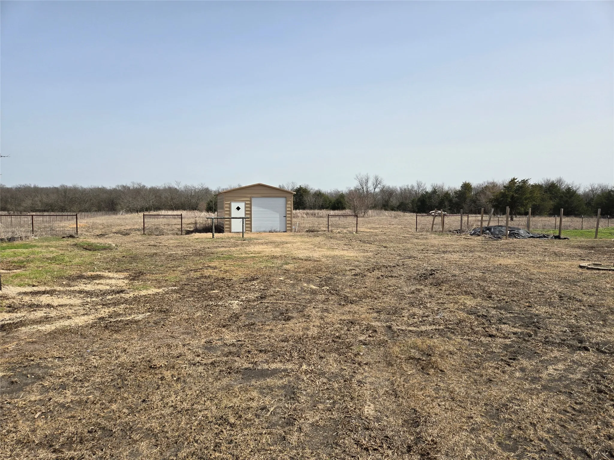 View of yard featuring an outbuilding, a rural view, a detached garage, and fence