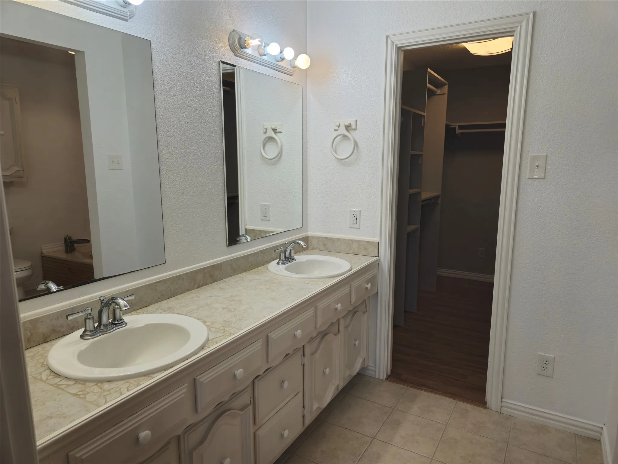 Bathroom featuring tile patterned floors, double vanity, a walk in closet, and a sink