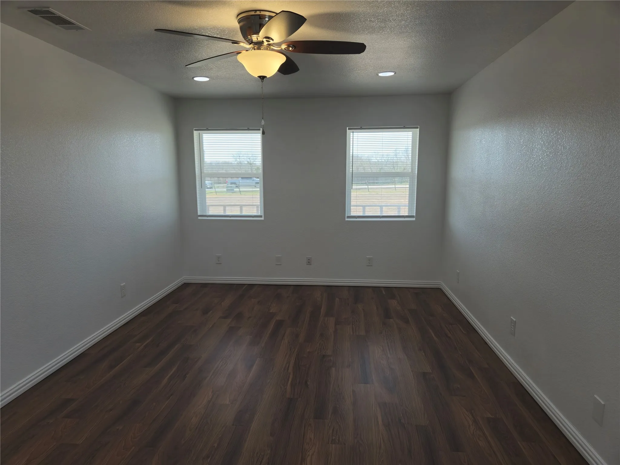 Empty room with a wealth of natural light, visible vents, a textured ceiling, and baseboards
