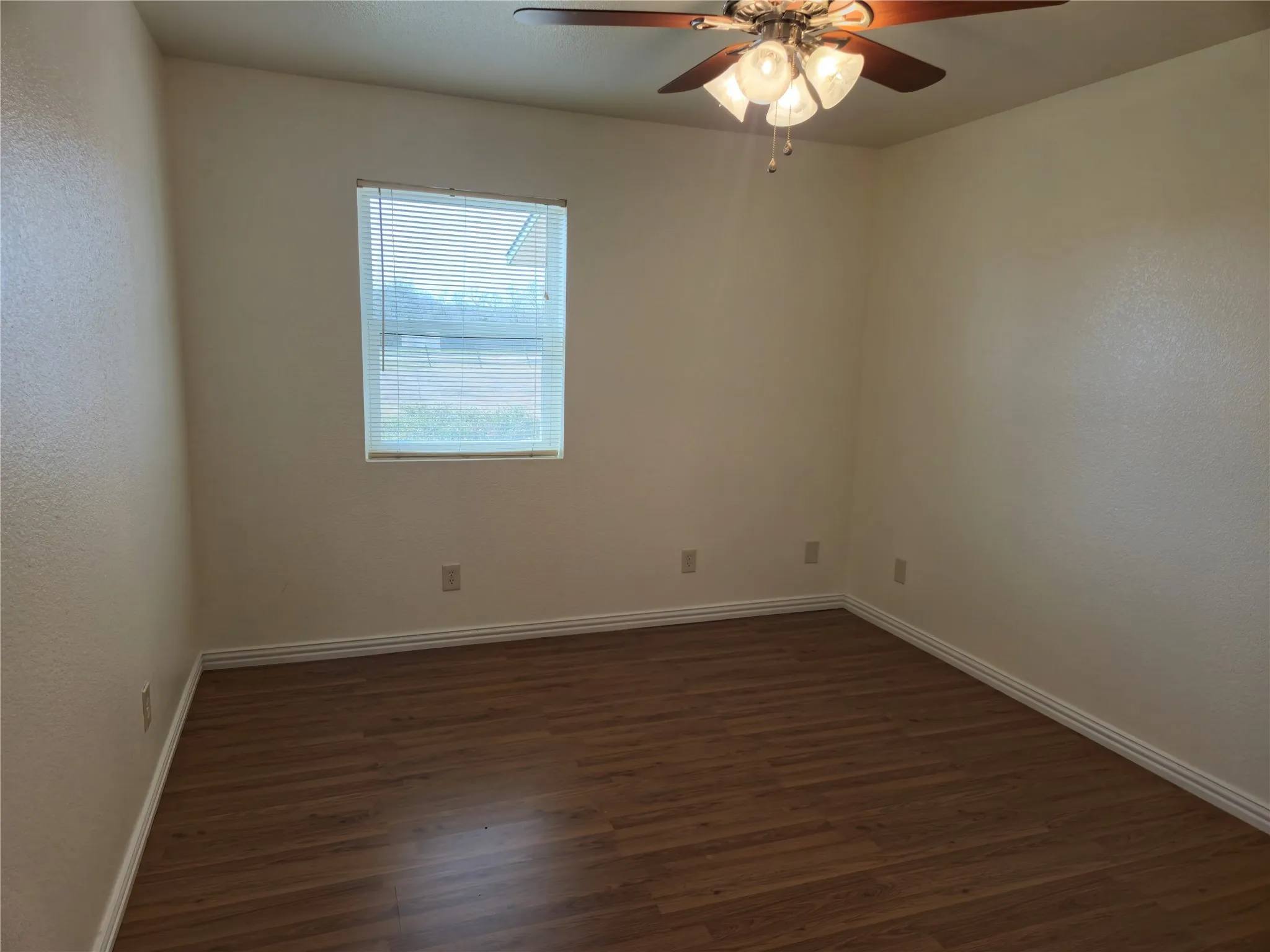 Unfurnished room with a ceiling fan, dark wood-style floors, and baseboards