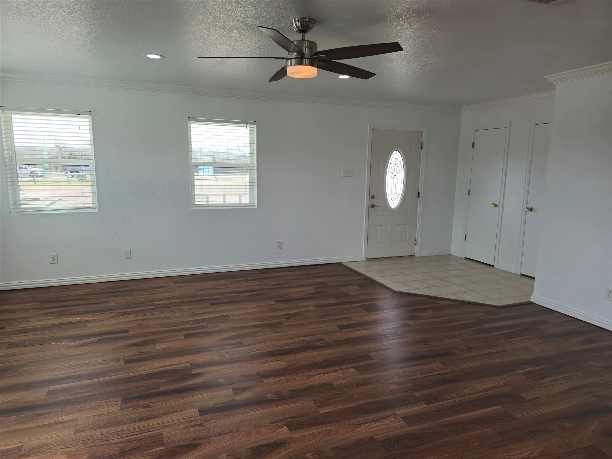 Foyer entrance with baseboards, wood finished floors, a textured ceiling, and ornamental molding
