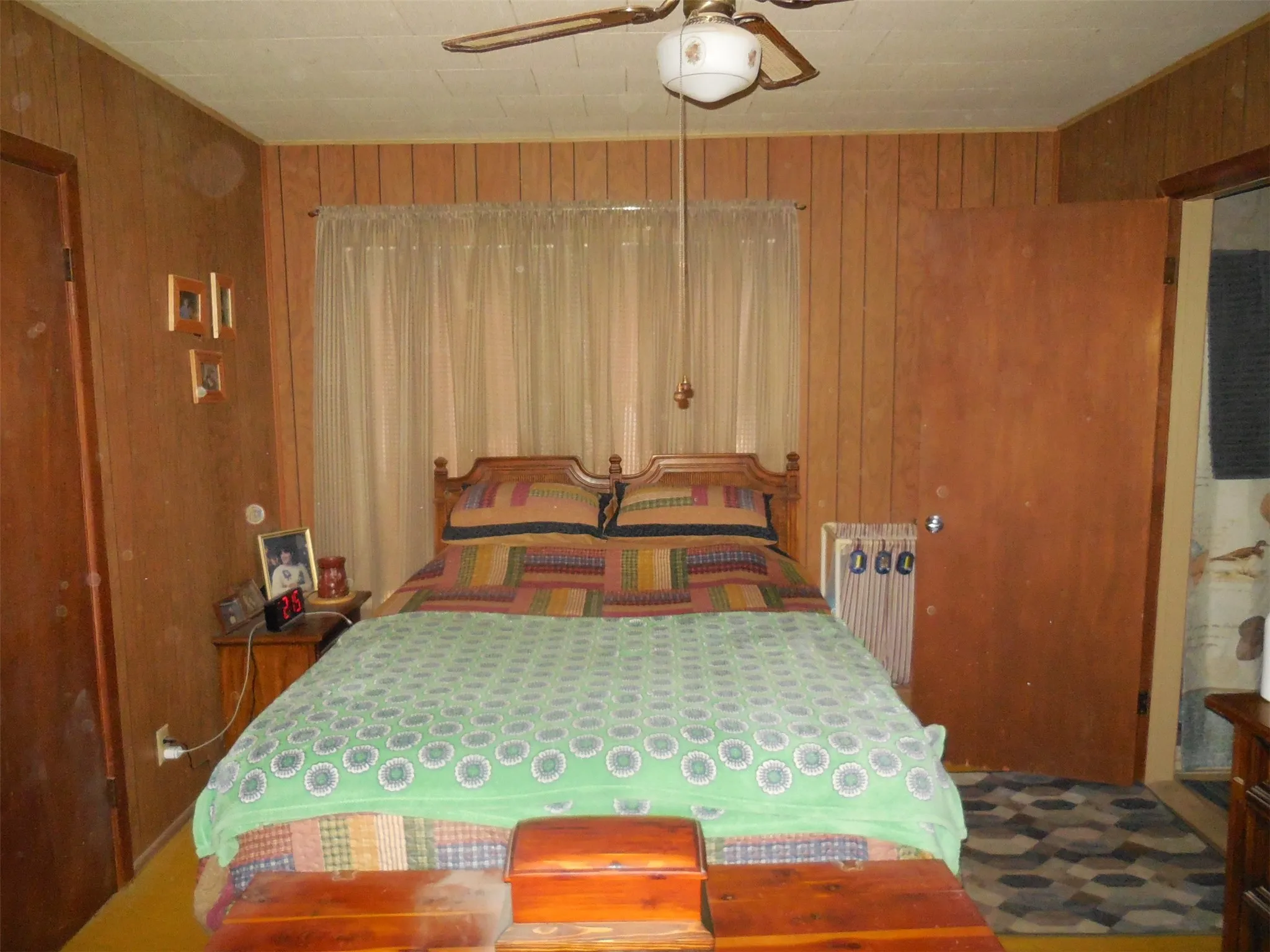Bedroom featuring wooden walls, and a ceiling fan