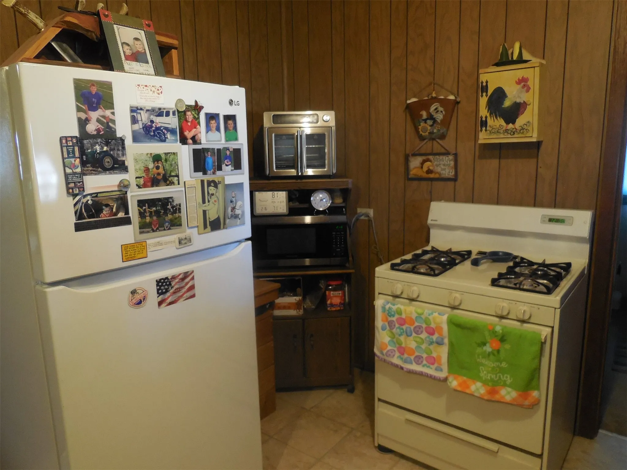 Kitchen featuring white appliances, light tile patterned flooring, and wood walls